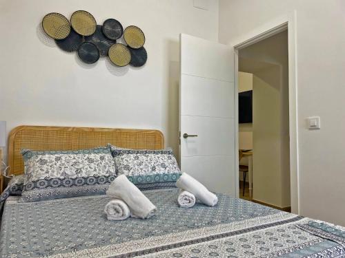 a bedroom with a bed with towels and hats on the wall at Apartamento J Burgos - Ole Solutions in El Puerto de Santa María
