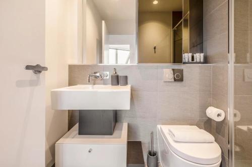a white bathroom with a sink and a toilet at West Side Explore Downtown Melb in Chic Condo in Melbourne