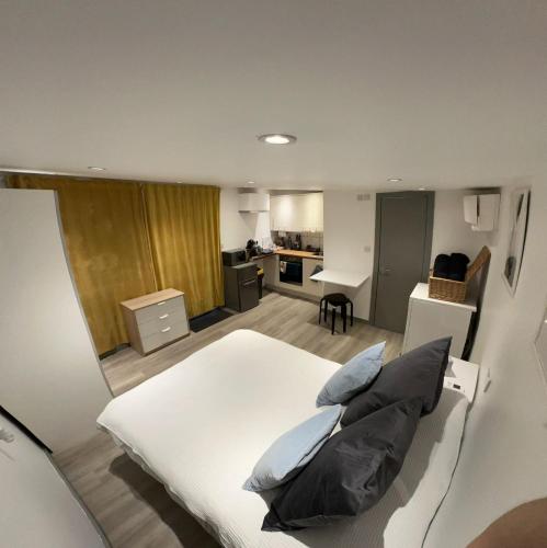 a bedroom with a white bed and a kitchen at Cosy, self-contained guest house in Thornton Heath