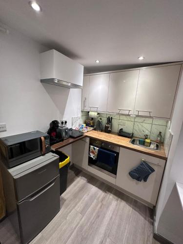 a small kitchen with white cabinets and a sink at Cosy, self-contained guest house in Thornton Heath