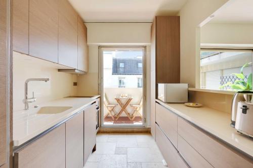 une cuisine avec des placards blancs et une grande fenêtre dans l'établissement Chic apartment - 1BR-4P - Place des Vosges, à Paris