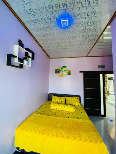 a bedroom with a yellow bed and a ceiling at Villa Hasanah in Subang
