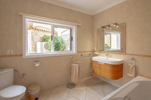 a bathroom with a toilet and a sink and a window at Villa Victoria With Heated Pool in Callao Salvaje