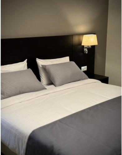 a large bed with white sheets and pillows at 365 UrbanLiving in Jbeil