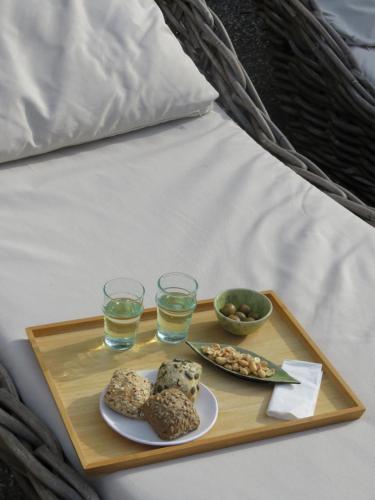 uma bandeja com dois copos de água e comida em uma cama em Clori Gaeta em Gaeta