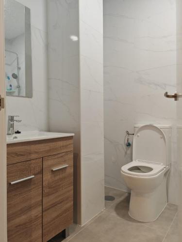 a white bathroom with a toilet and a sink at Hotel Golden Alcorcon in Alcorcón