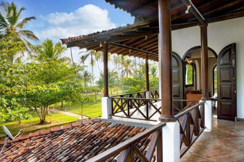 a porch of a house with palm trees in the background at Villa Ocean's Edge in Ranna