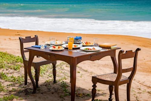 a table with plates of food on the beach at Villa Ocean's Edge in Ranna