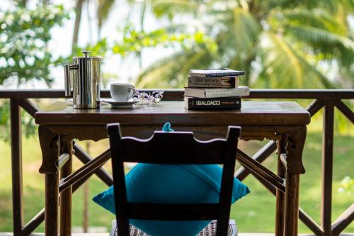 a table with books and a cup of coffee and a chair at Villa Ocean's Edge in Ranna