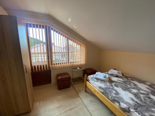a bedroom with a bed and a desk and two windows at Анелия in Sapareva Banya
