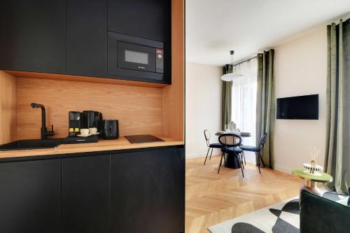 une cuisine avec des armoires noires et un salon dans l'établissement Parisian with air conditioning Eiffel Tower, à Paris