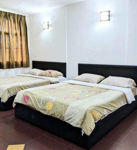 two beds sitting next to each other in a bedroom at EnE Sri Cemerlang in Kota Bharu