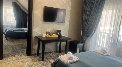 a hotel room with a table and a tv on the wall at Poarta Raiului in Tău Bistra