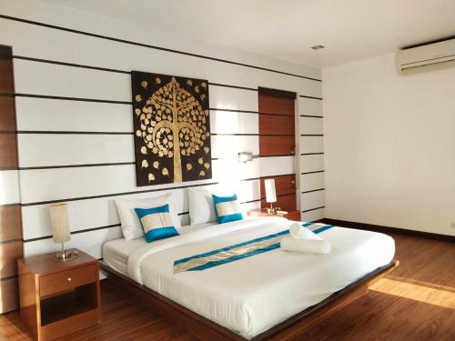 a bedroom with a large white bed with blue pillows at The Phura Villa Khaolak - SHA Extra Plus in Khao Lak