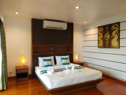 a bedroom with a large white bed with blue pillows at The Phura Villa Khaolak - SHA Extra Plus in Khao Lak