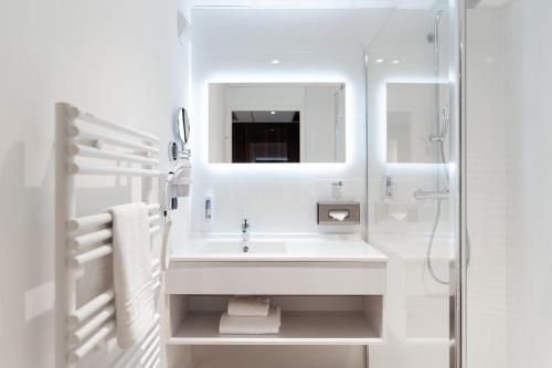 a white bathroom with a sink and a mirror at Westotel Taverny - Paris Val-d'Oise in Taverny