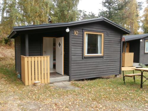 a black shed with a porch and a table at Tylebäck - boende med självhushåll in Halmstad