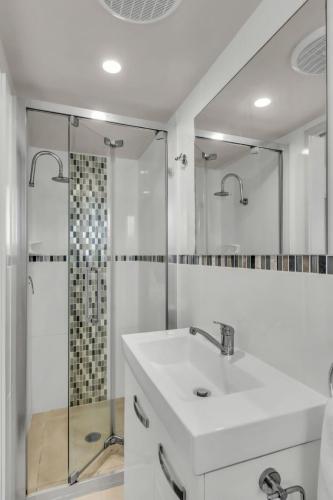 a white bathroom with a sink and a shower at Baywatch 5 in Merimbula