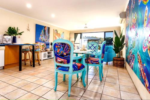 a kitchen with blue chairs and a table at Sails 5 in Merimbula