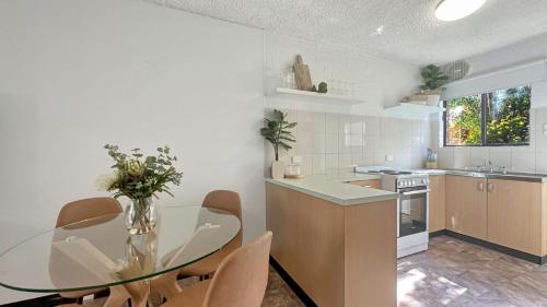 a kitchen with a glass table and a table and chairs at The Essentials Unit 2 - 1 Marine Parade in Merimbula