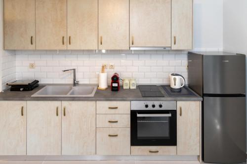 a kitchen with wooden cabinets and a stainless steel refrigerator at Το Σπίτι της Γιαγιάς 2 (Grandma's House 2) in Kondopoúlion