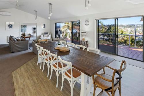 a dining room and living room with a large wooden table and chairs at Captains Quarters in Merimbula