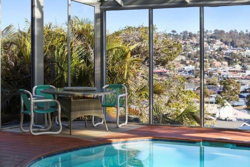 a patio with a table and chairs next to a swimming pool at Captains Quarters in Merimbula