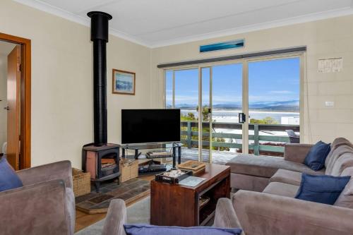 a living room with a fireplace and a flat screen tv at Cliffhanger in Merimbula