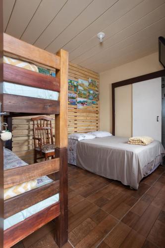a bedroom with two bunk beds and a chair at Pousada Dona Elena in Penha