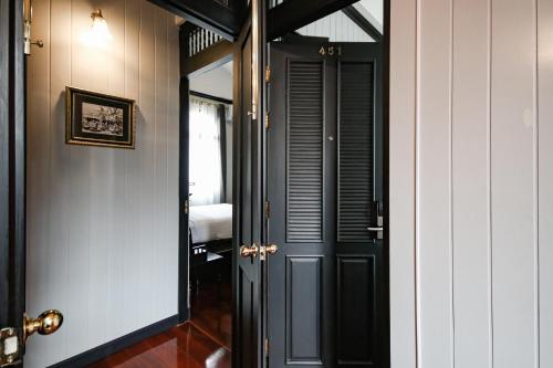a hallway with a black door and a mirror at DE Phanakron Boutique Hotel in Bangkok