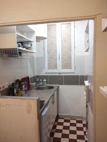 une petite cuisine avec un évier et une fenêtre dans l'établissement Charmant studio en centre ville, à Saint-Ouen