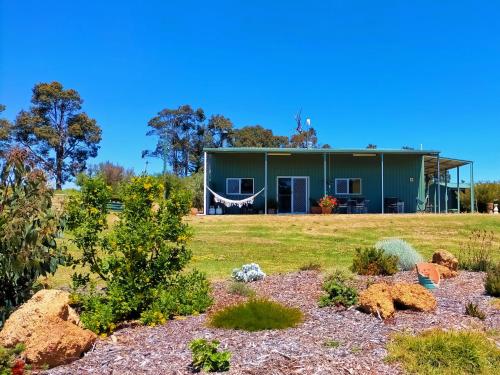 a green house on a hill with a yard at 2 bedroom farm stay in Metricup at Qwack's Farm in Metricup