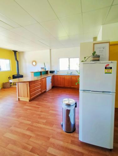 a kitchen with a white refrigerator and a wooden floor at 2 bedroom farm stay in Metricup at Qwack's Farm in Metricup