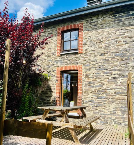 TennevilleにあるLa balade en forêt - gîte 9 personnes en Ardenneの石造りの建物前の木製のピクニックテーブル