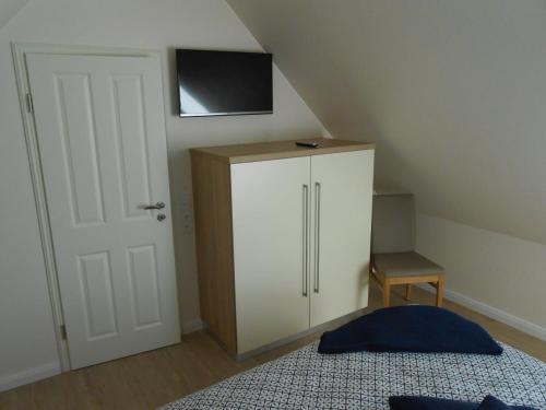 a bedroom with a white cabinet with a television on the wall at Emsdüne in Borkum