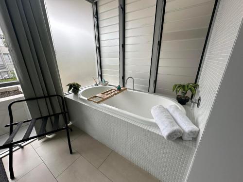 a white bathroom with a tub and a chair at Aquatic Dreaming at 1 Bright Point, Nelly Bay Magnetic Island in Nelly Bay