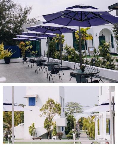 a group of tables and chairs with an umbrella at The Arjana Resort in Masjid Tanah