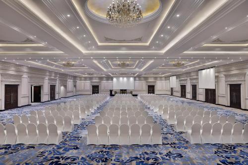 a large banquet hall with white chairs and a chandelier at Voco - Riyadh by IHG in Riyadh