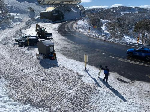 a person standing on the side of a road in the snow at Higgi Drive 1 Ski-In Ski-Out in Mount Hotham
