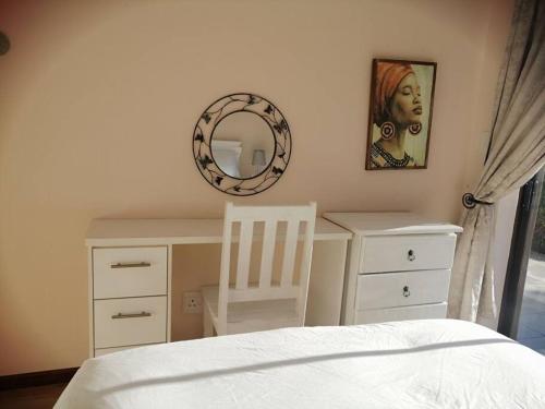 a bedroom with a desk and a mirror and a chair at Hartenbos Tranquility in Mossel Bay
