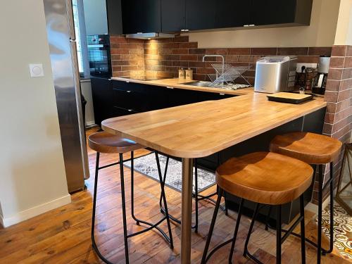 - une cuisine avec une table et des tabourets en bois dans l'établissement Le nid kalain, à Bourg-lès-Valence