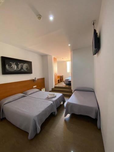 a bedroom with two beds and a television at Hostal Drassanes in Barcelona