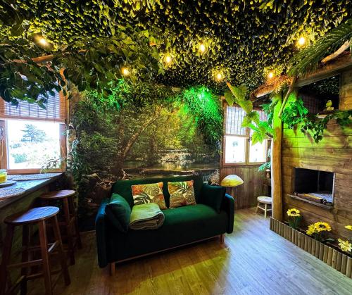 a living room with a green couch and a tree wall at Les Chambres de Paulette à Theme LA JUNGLE ROOM in Sainte-Marie-la-Mer