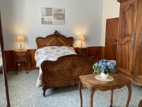 a bedroom with a bed and a table with flowers on it at Le petit gîte du theil au servant in La Chapelle-Viviers