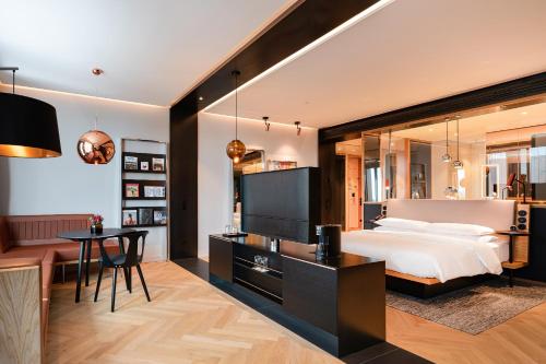 ein Schlafzimmer mit einem großen Bett, einem Schreibtisch und einem Tisch in der Unterkunft Andaz Munich Schwabinger Tor, By Hyatt in München