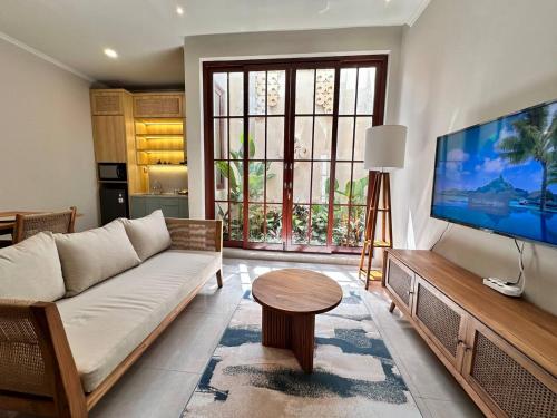 a living room with a couch and a large flat screen tv at Putu Soemantri Four Persons Villas in Denpasar