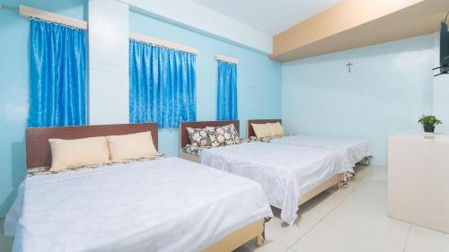 two beds in a room with blue walls and windows at CM Apartelle Iloilo International Airport by RedDoorz in Cabatuan