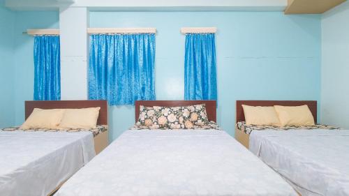 two beds in a room with blue walls and blue curtains at CM Apartelle Iloilo International Airport by RedDoorz in Cabatuan