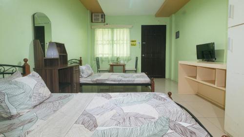 a bedroom with two beds and a television in it at CM Apartelle Iloilo International Airport by RedDoorz in Cabatuan