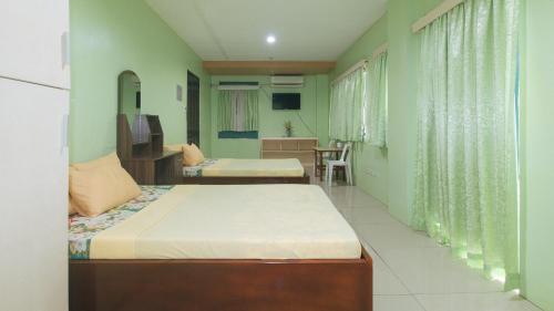 a bedroom with two beds and a desk and a table at CM Apartelle Iloilo International Airport by RedDoorz in Cabatuan
